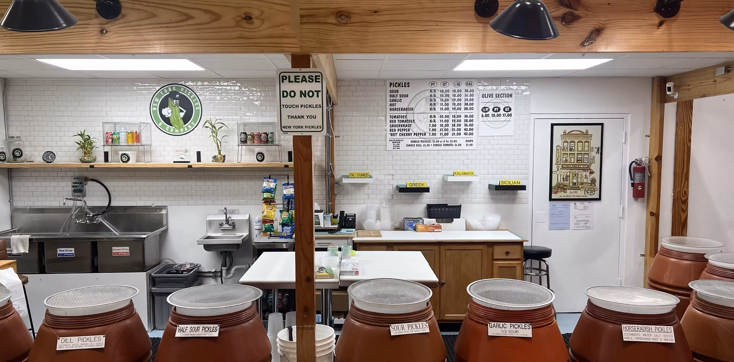 Interior of a pickle shop with labeled pickle barrels and a sign saying not to touch pickles.