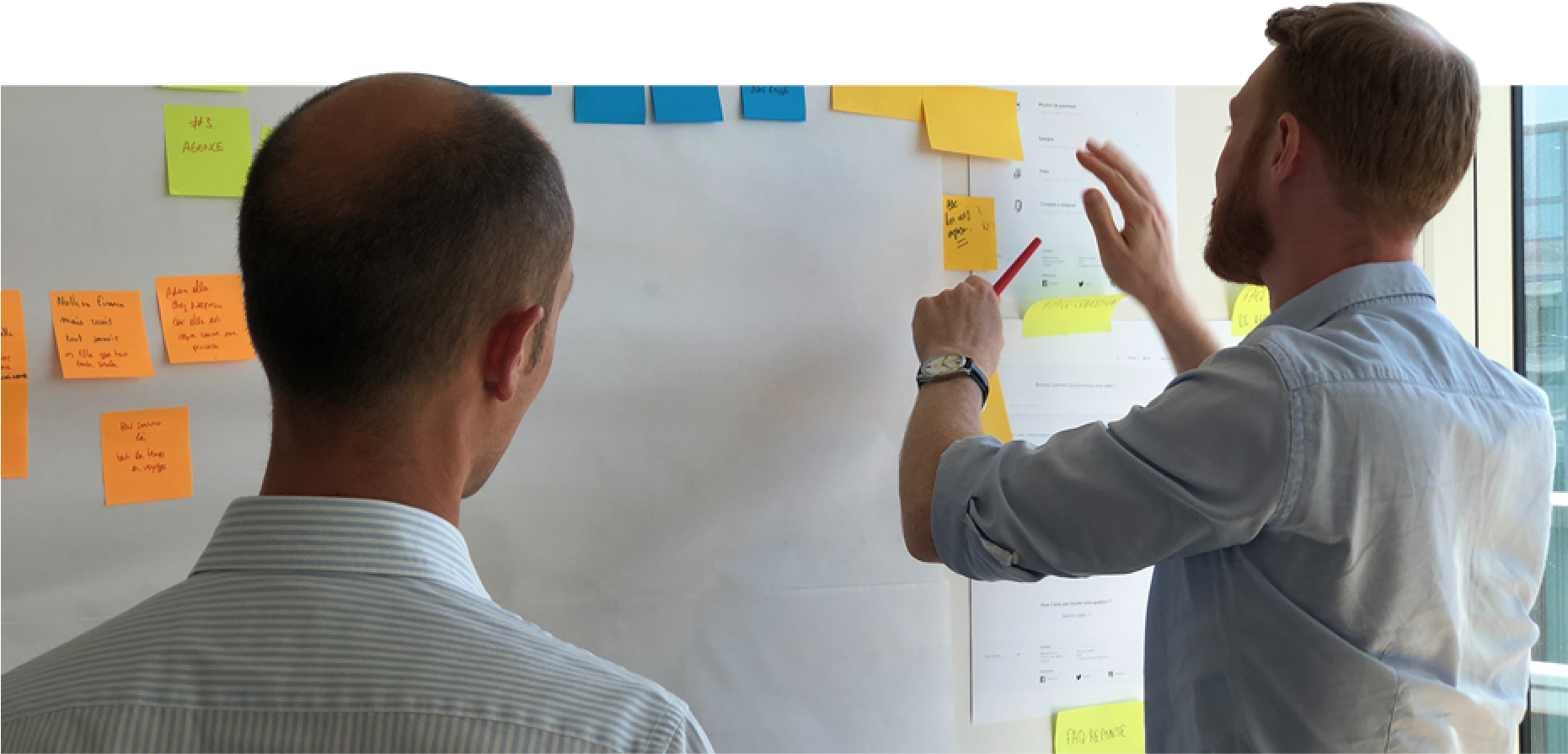 Two team members at a whiteboard of sticky notes, planning the migration