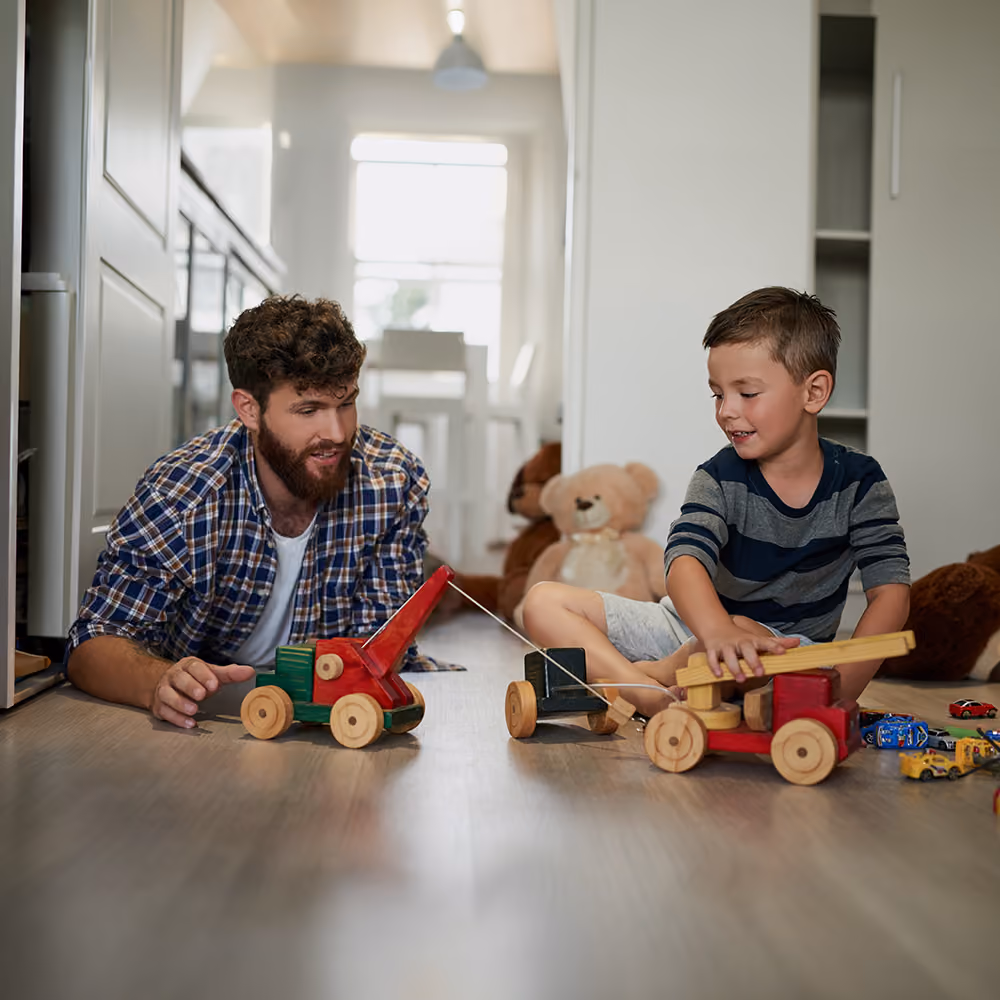 Male therapist sitting on the floor playing with a young boy in a play therapy room