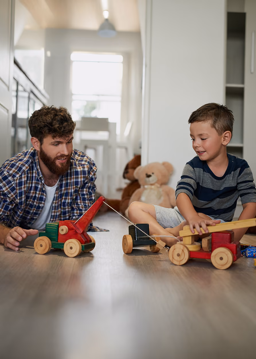 Male therapist sitting on the floor playing with a young boy in a play therapy room