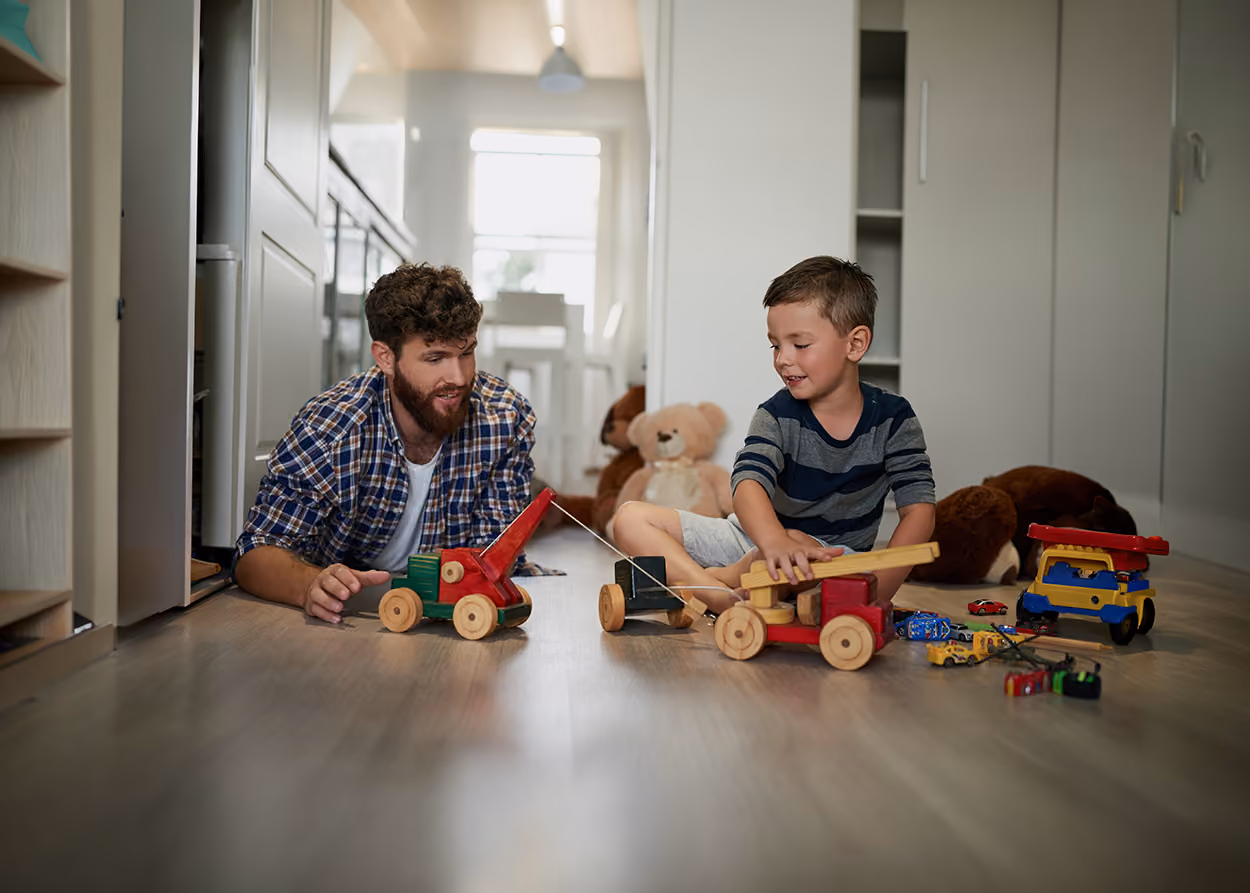 Male therapist sitting on the floor playing with a young boy in a play therapy room