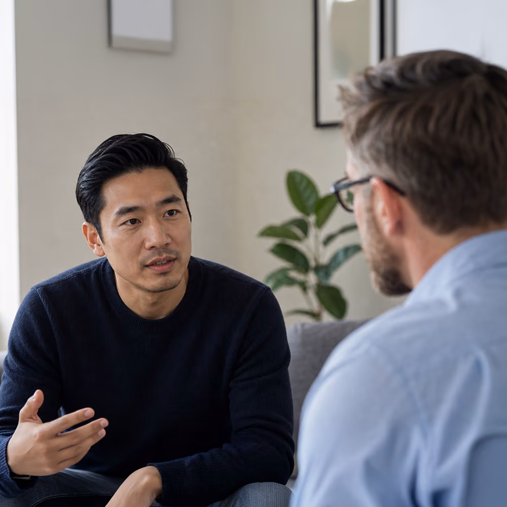 Two people in a warm therapy office having an open, calm conversation