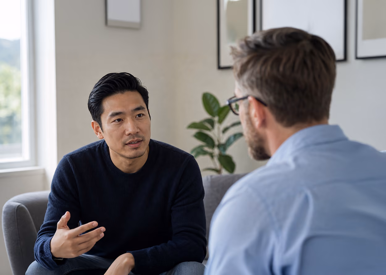 Two people in a warm therapy office having an open, calm conversation