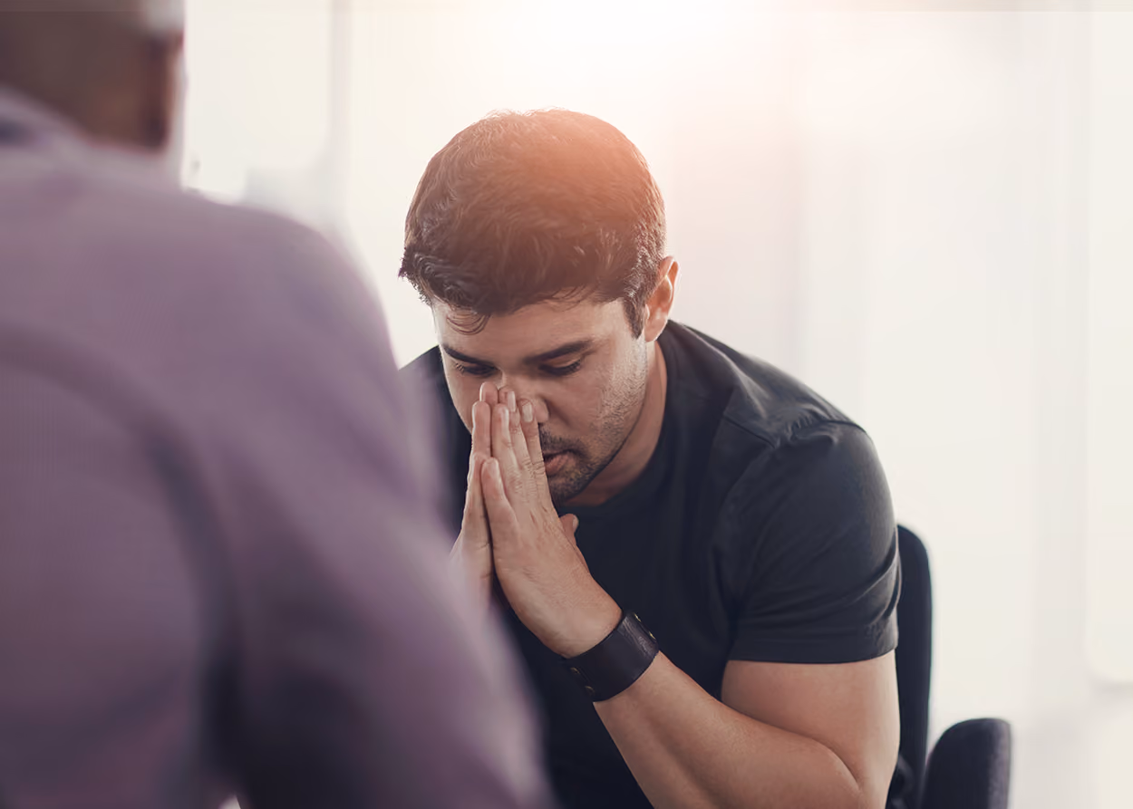 Adult client and therapist sitting across from each other in a comfortable therapy office