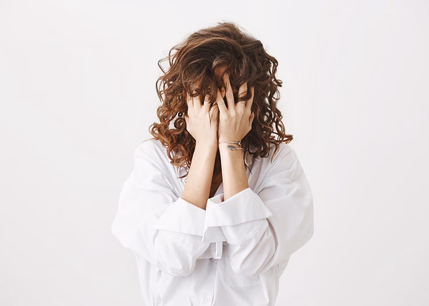 Woman holding her hand over her face, overwhelmed with anxiety.