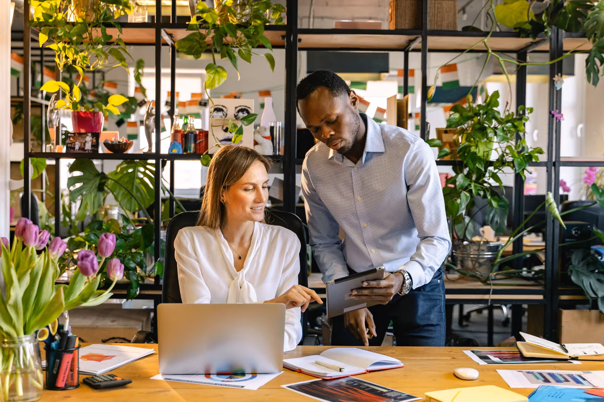 Two coworkers in a workplace setting working together at a table. 