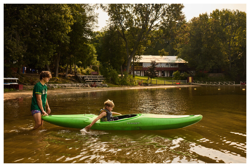 A camper and counsellor launching a kayak on Gull Lake