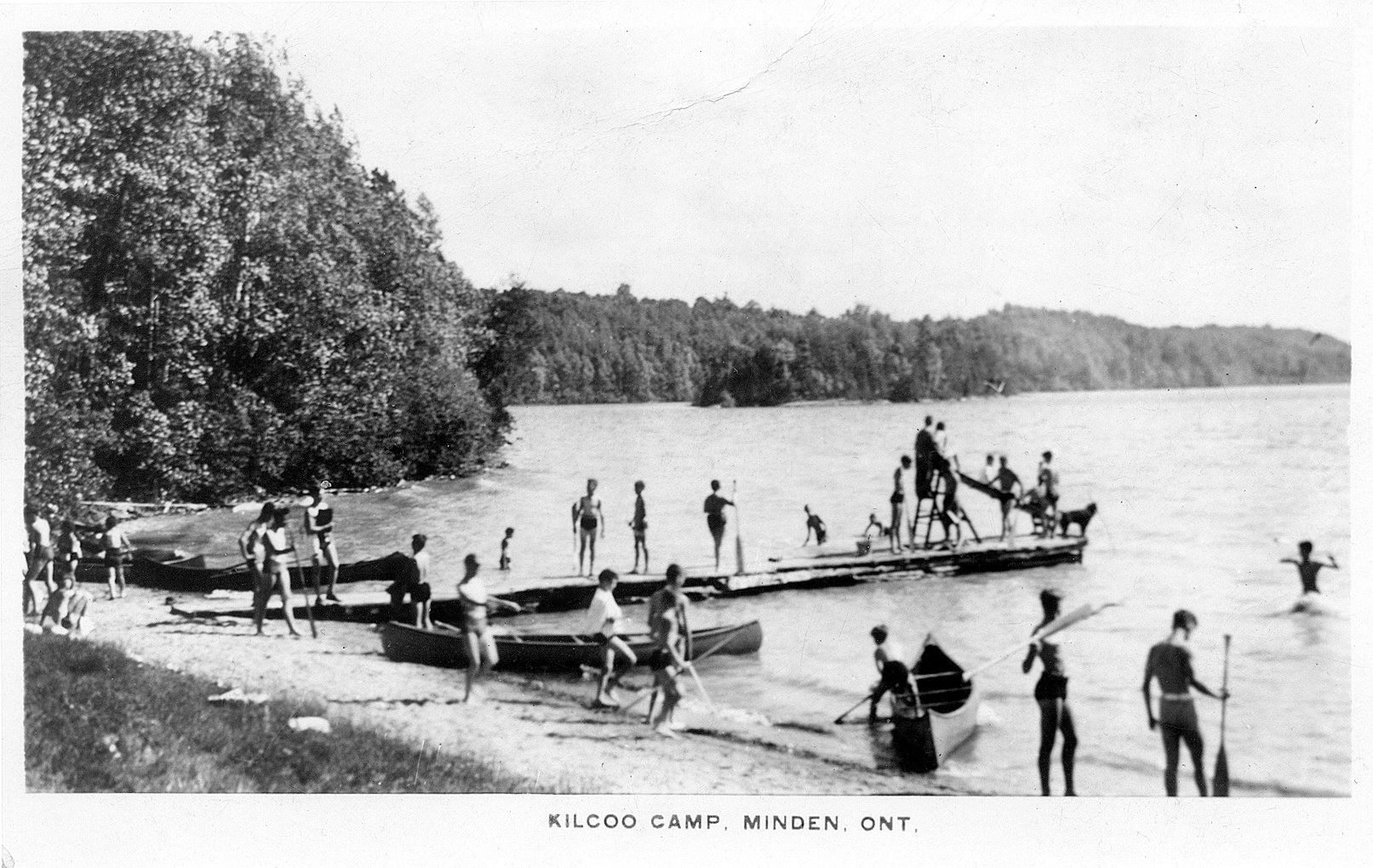 Archival postcard of the Kilcoo Camp waterfront with campers and canoes, Minden, Ontario