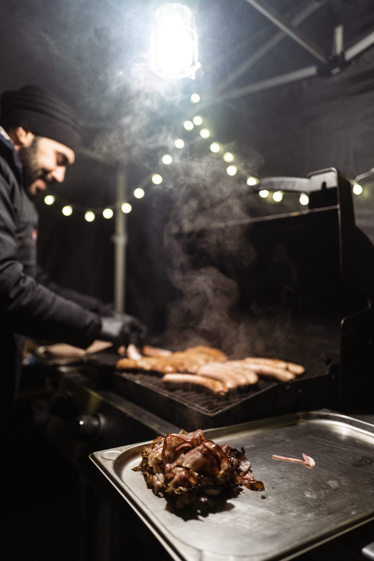 Weihnachtsgrillen unter Lichterketten, Fleisch auf dem Rost