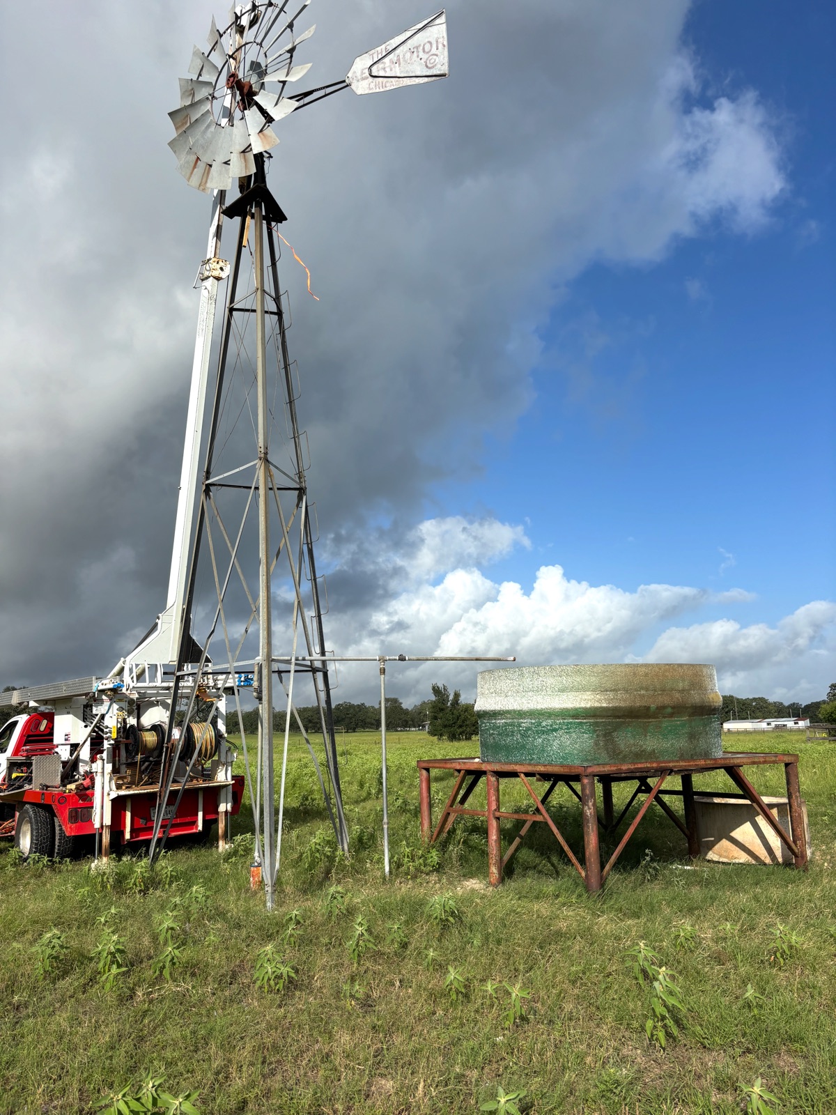 Windmill and elevated stock tank with T&A service truck on a ranch near McDade, Texas