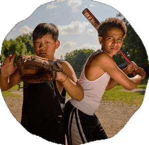 Two campers stand back to back on a grassy field, one holding a baseball glove, the other a bat.