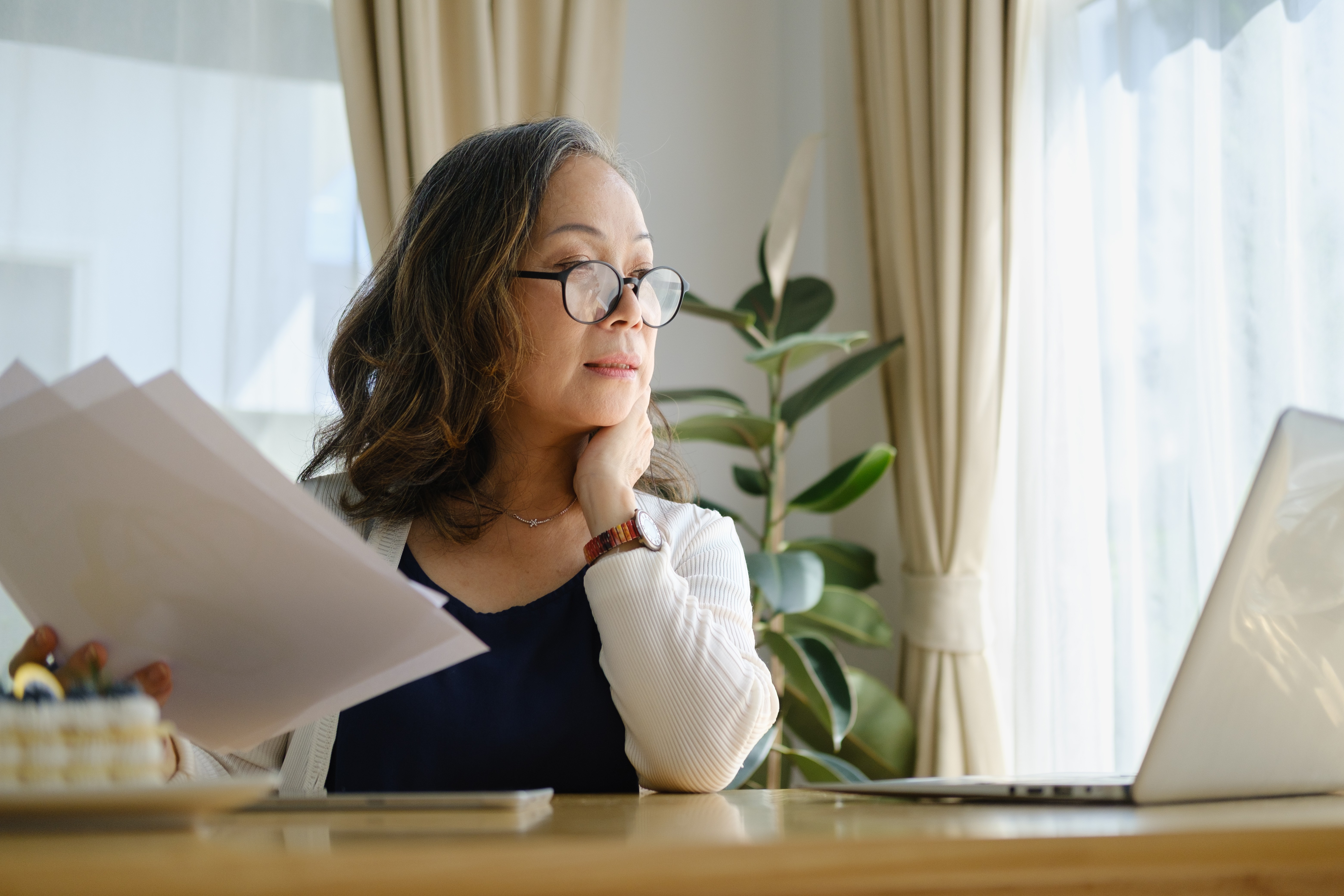Woman reviewing papers at a desk with a laptop