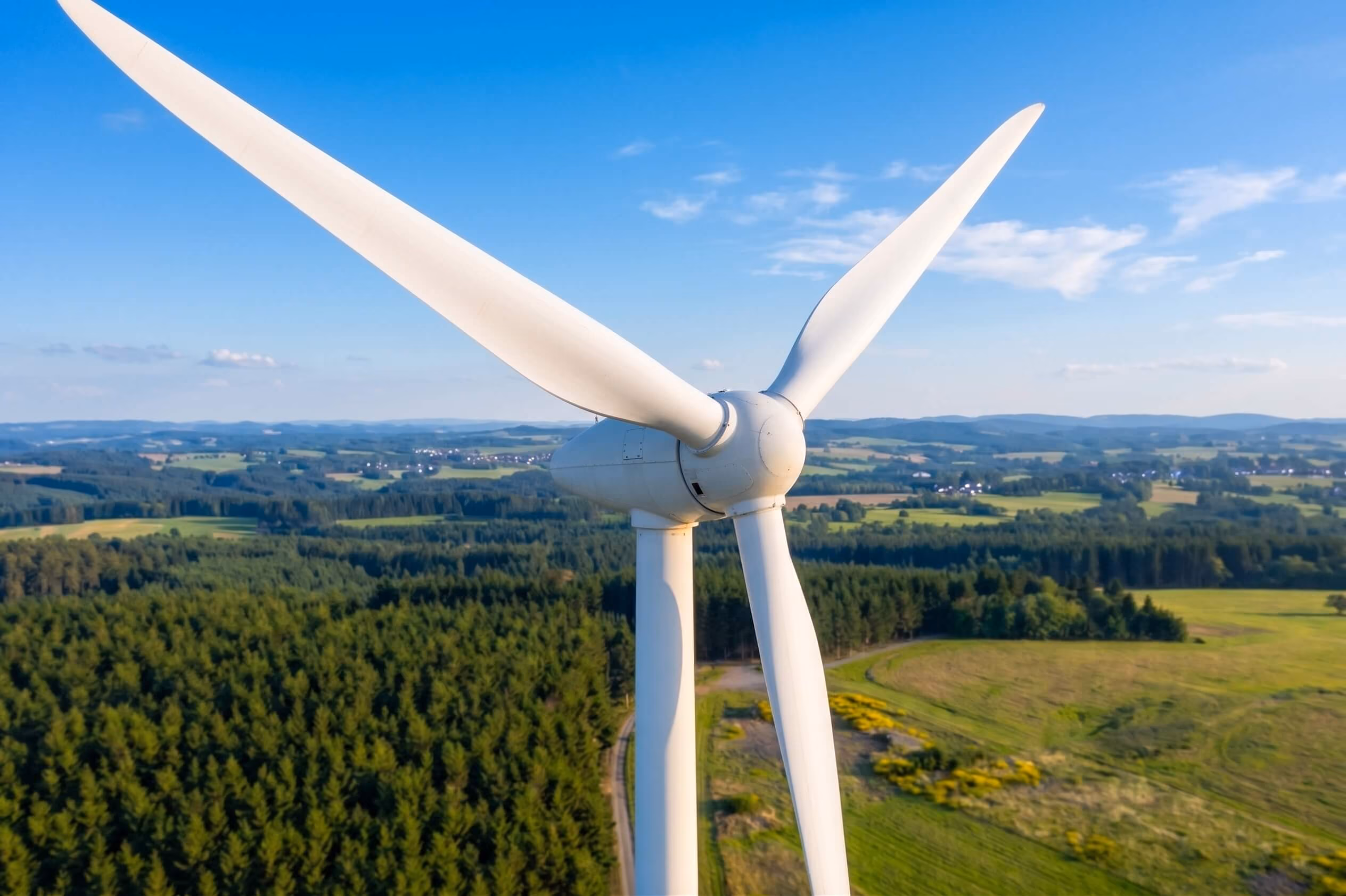 Wind turbines spread across green rolling hills under a cloudy sky for sustainable energy.