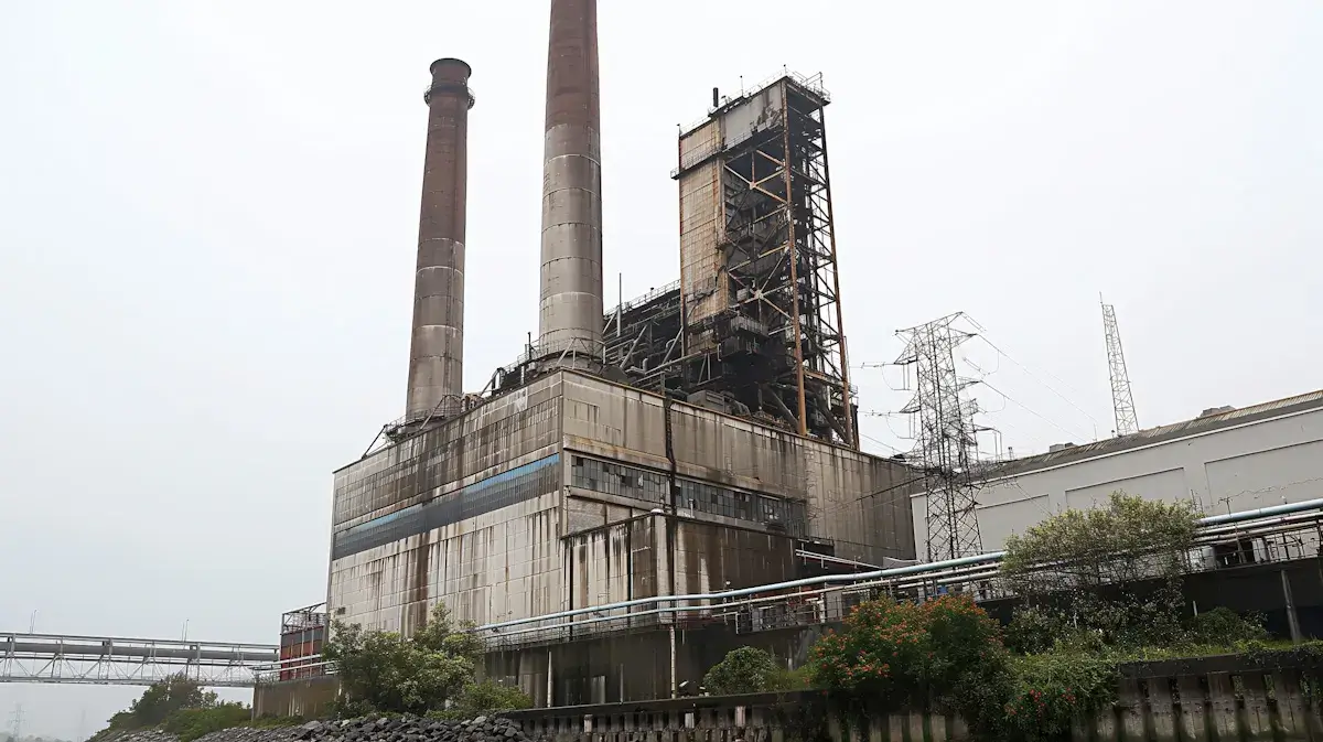 Exterior view of an old industrial power plant facility with tall concrete smokestacks near a body of water