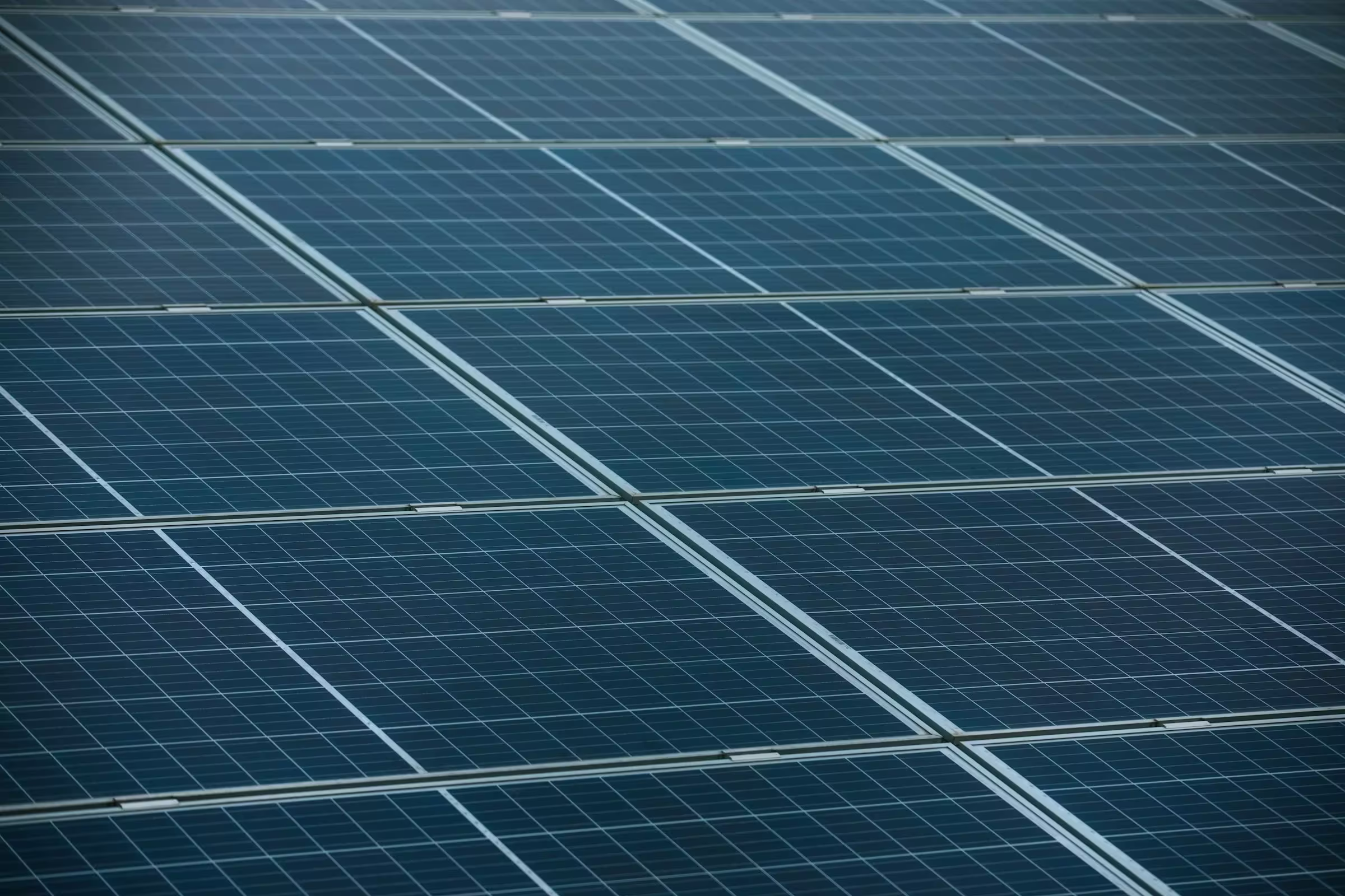 Close-up view of multiple dark blue solar panels with visible grid patterns and silver framing lines.