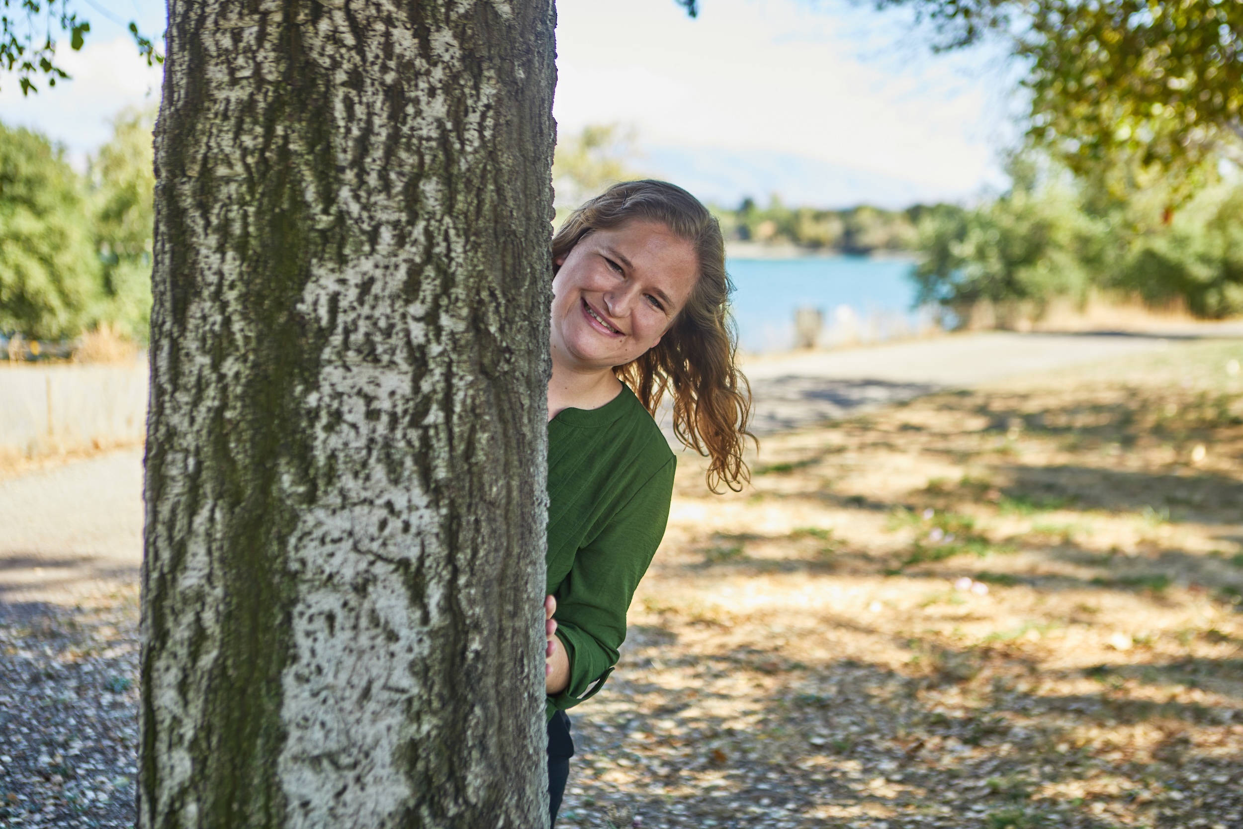 Hannah Ly, LMFT, child and play therapist and founder of Your Therapy Nook, smiling from behind a tree
