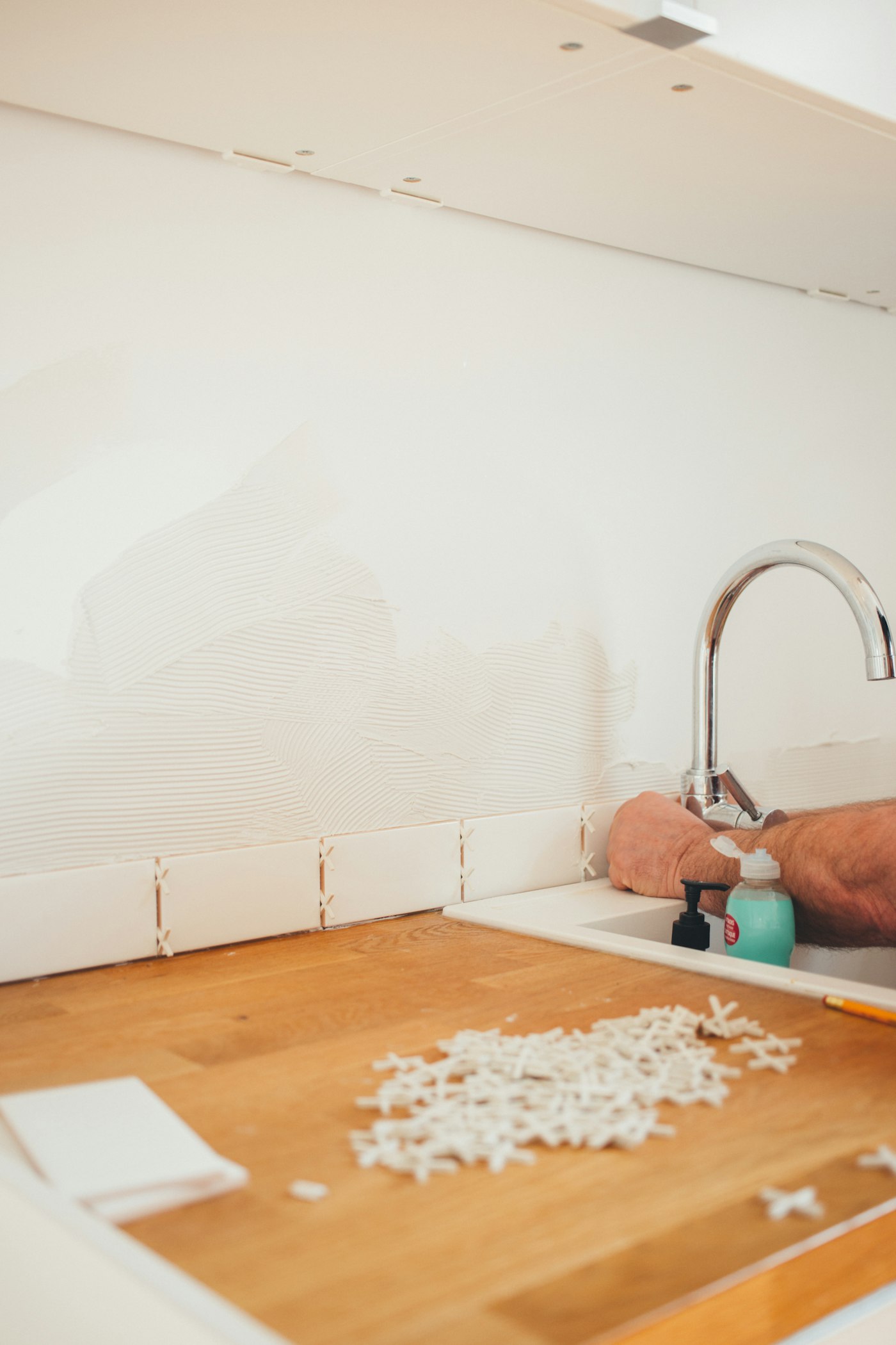 Plumber installing a chrome kitchen faucet during a renovation