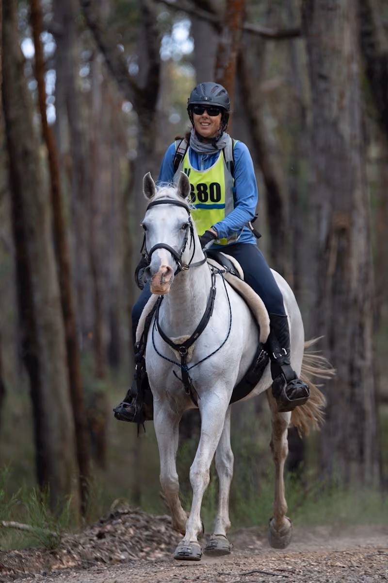Dr Tanya Meares, Veterinarian at Western Victoria Vets, riding a grey horse through the bush