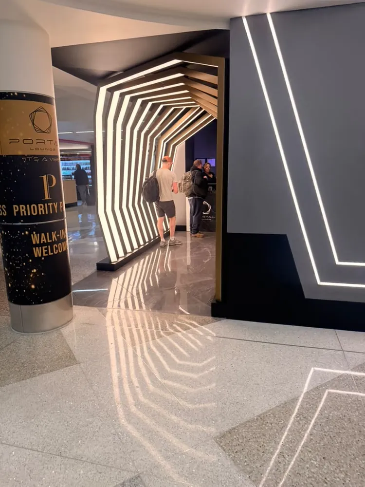 Lit hexagonal tunnel entrance to Portal Lounge at MSP Terminal 1, with a Priority Pass and walk-ins welcome sign