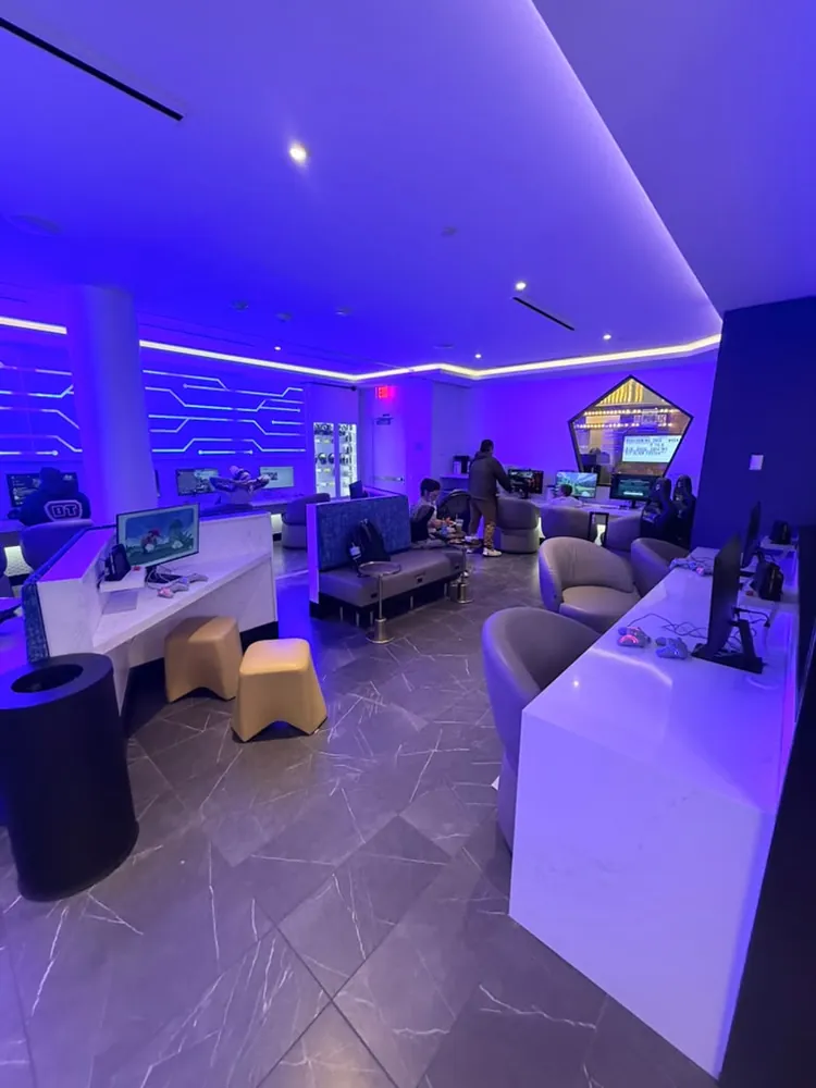 Gaming room inside Portal Lounge MSP with PC stations, gaming chairs and blue circuit board wall lighting