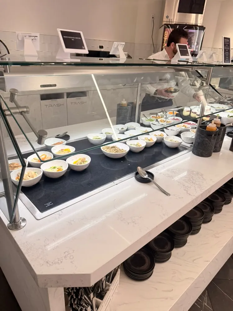 Food service counter at Portal Lounge MSP with individually plated dishes in small white bowls under glass