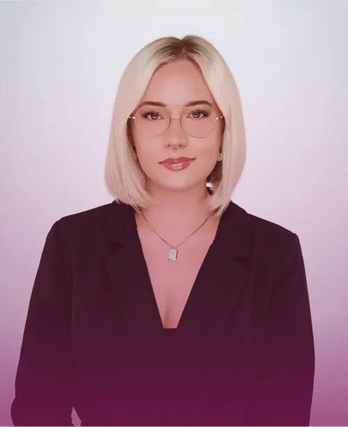 Frau mit blonden Haaren, Brille und schwarzem Blazer vor neutralem Hintergrund.