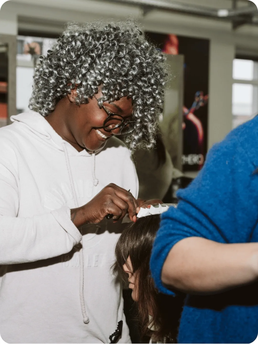 Lachende Teilnehmerin beim Haareschneiden an einem Modell im Unterricht der Deutschen Friseurakademie