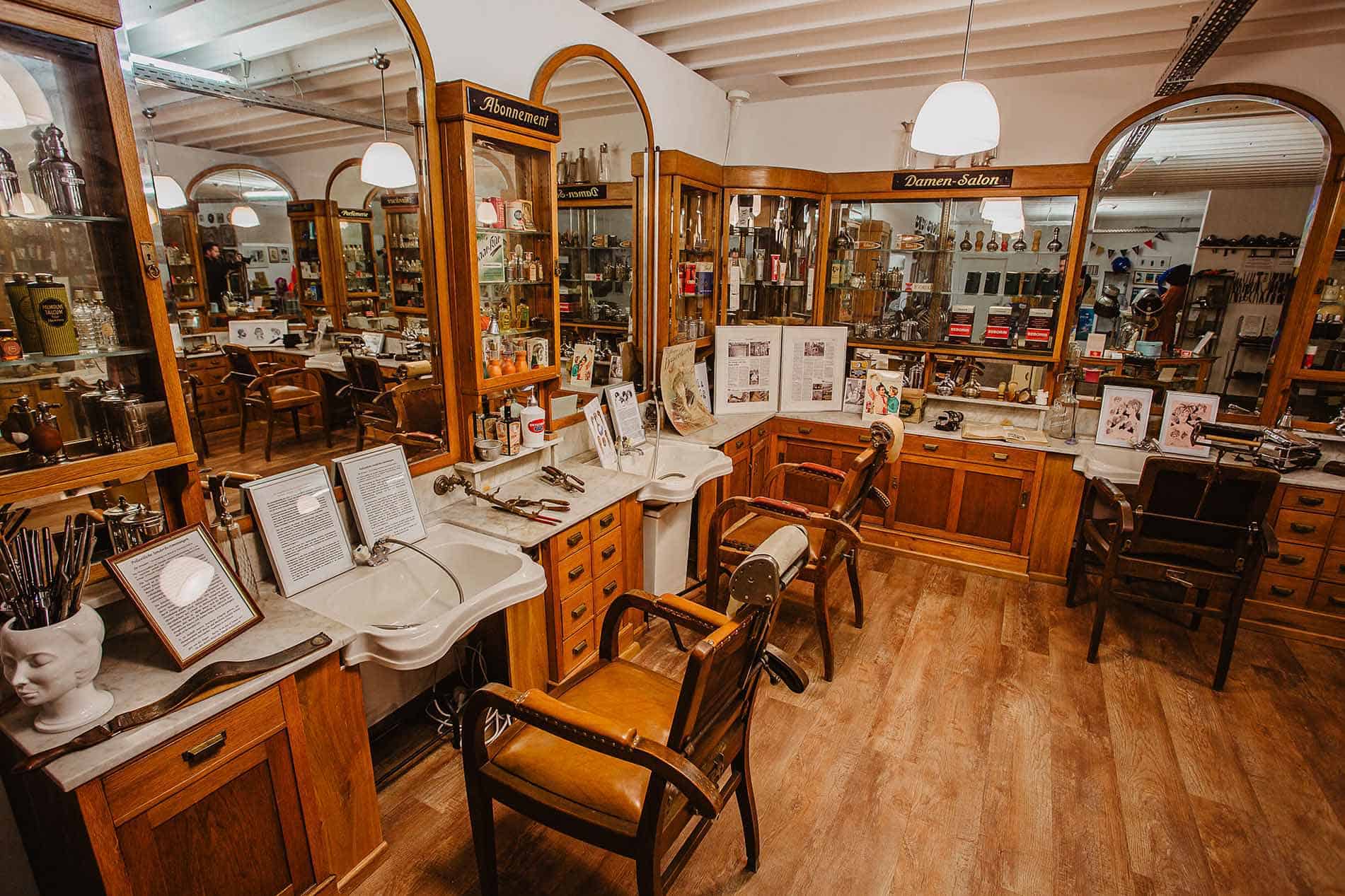 Nachgebauter historischer Damen-Salon im Friseurmuseum in Neu-Ulm mit Holzvitrinen, Spiegeln und Barbierstühlen
