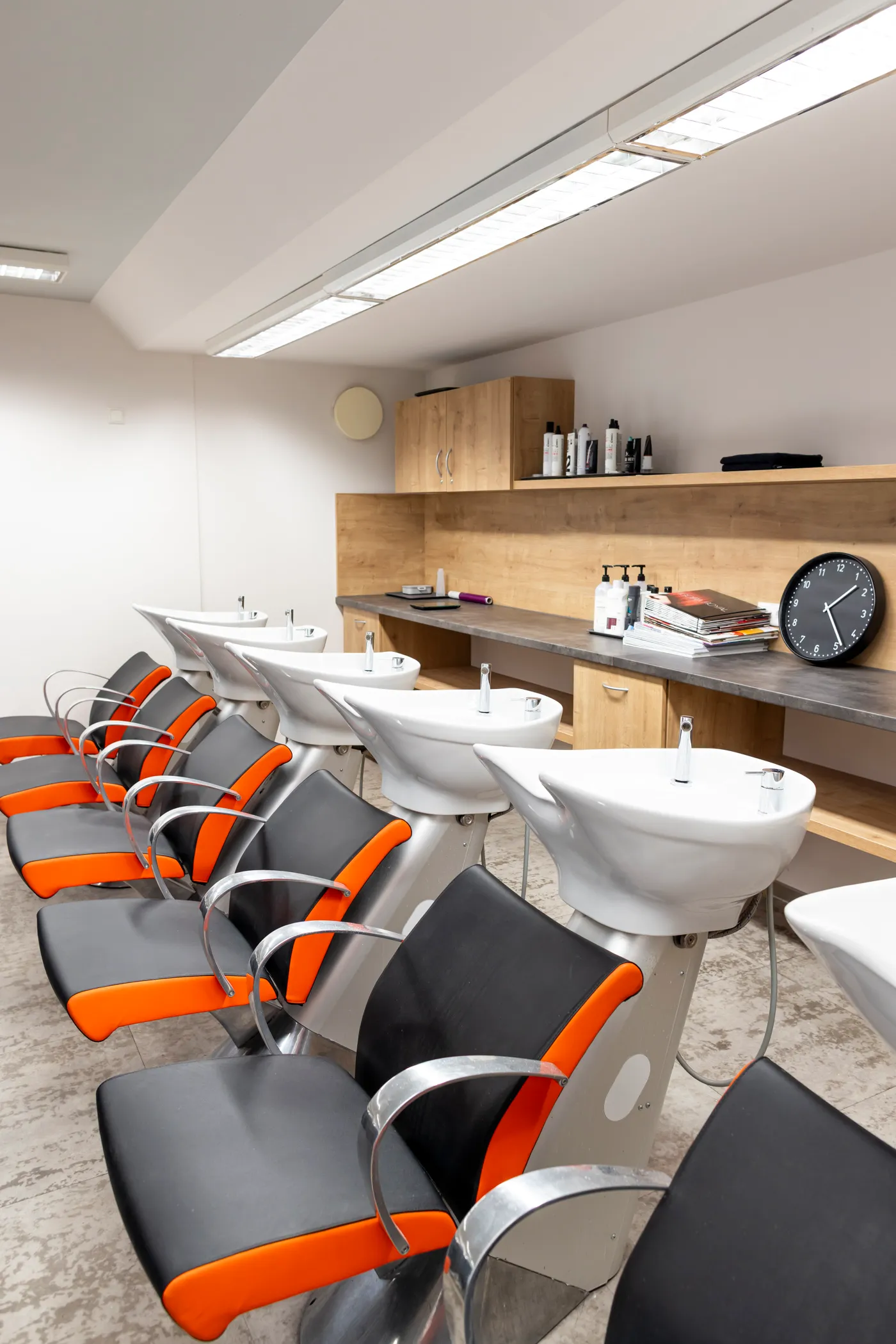 Praxisraum auf dem Friseurcampus Neu-Ulm mit Reihe von Waschplätzen, Bedienstühlen und Ablagen mit Friseurprodukten