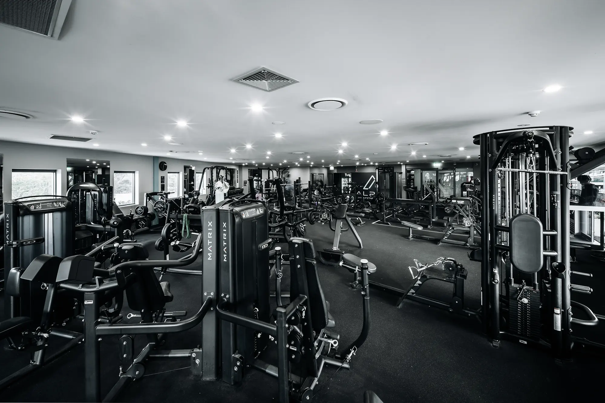 Interior view of a gym with various Matrix weight machines and fitness equipment under bright ceiling lights.