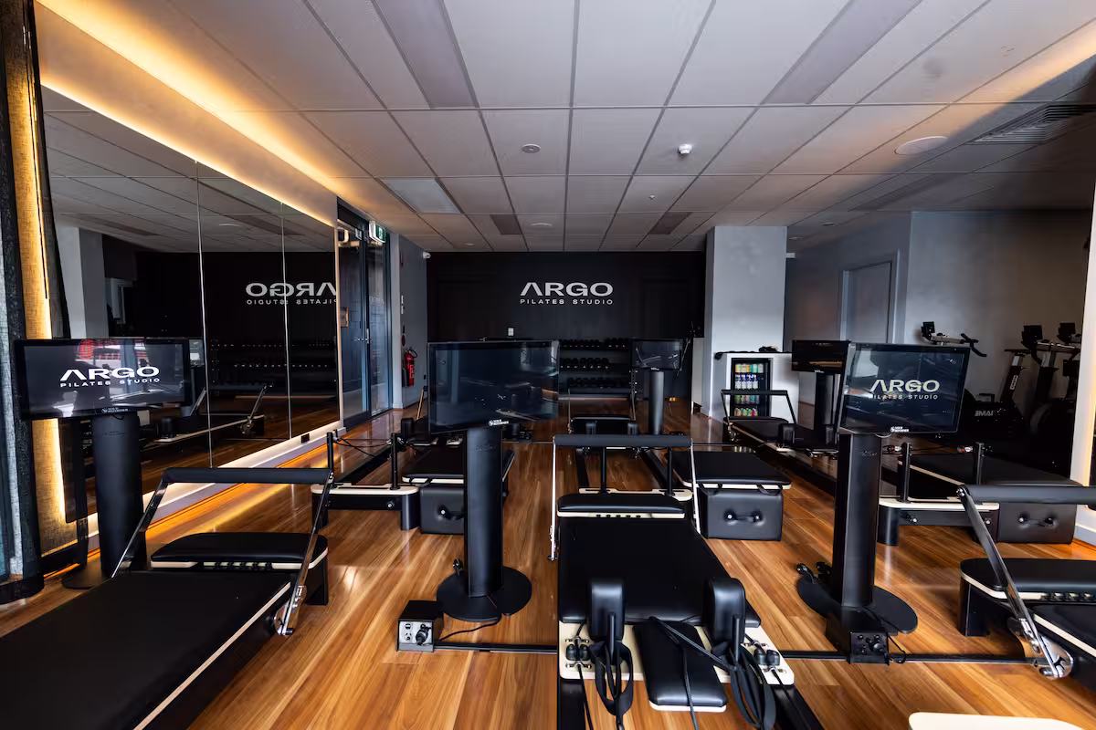 Interior view of Argo Pilates Studio with reformer machines and wood flooring.