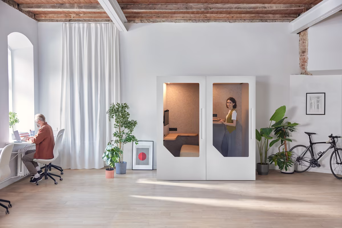 Person working inside an acoustic office booth in an open office environment