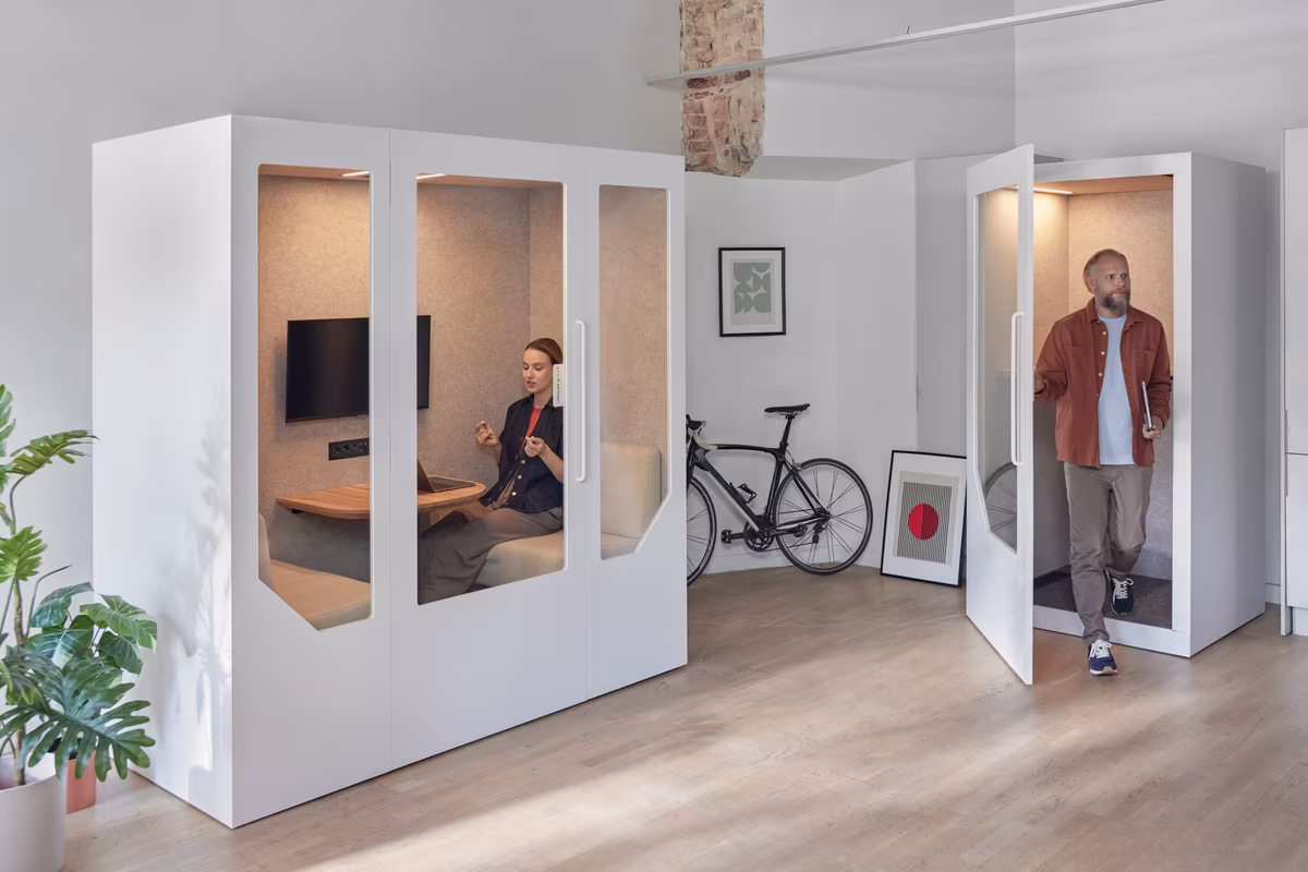 Person using an acoustic phone booth for a call inside an open office environment