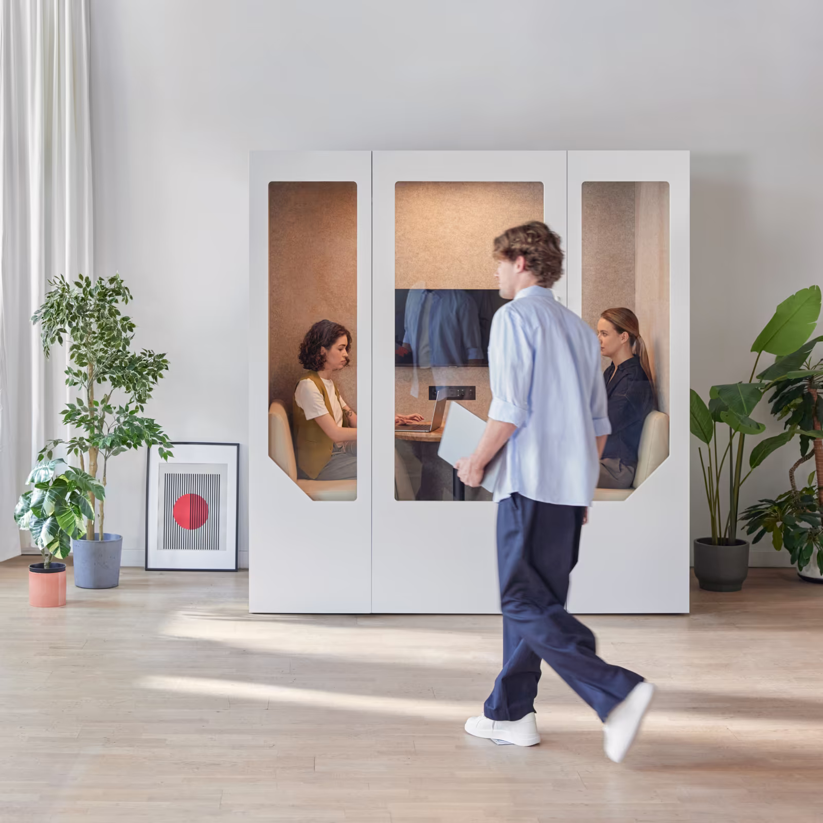 Team collaborating inside a meeting pod in an open-plan office workspace