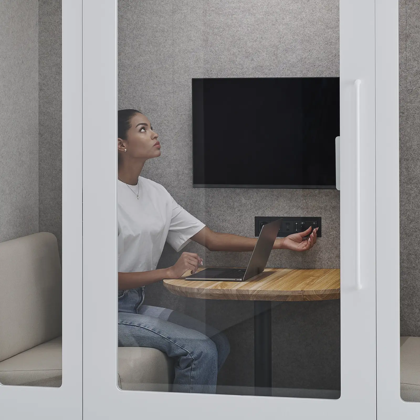 woman working inside a Persy meeting pod with laptop and screen