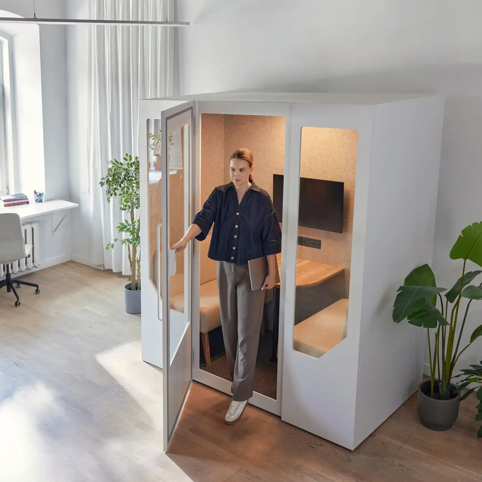 woman stepping out of a persy office pod in a bright open office