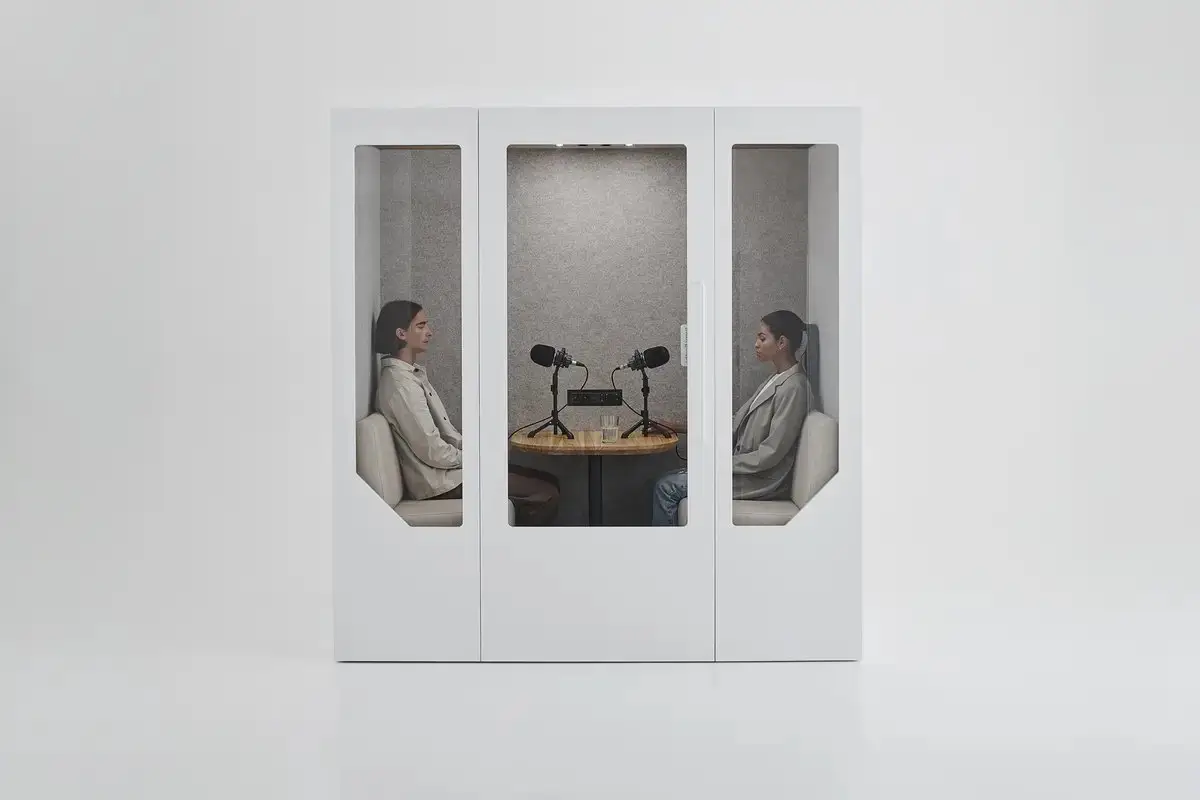 Two people in a meeting pod with microphones for a private discussion