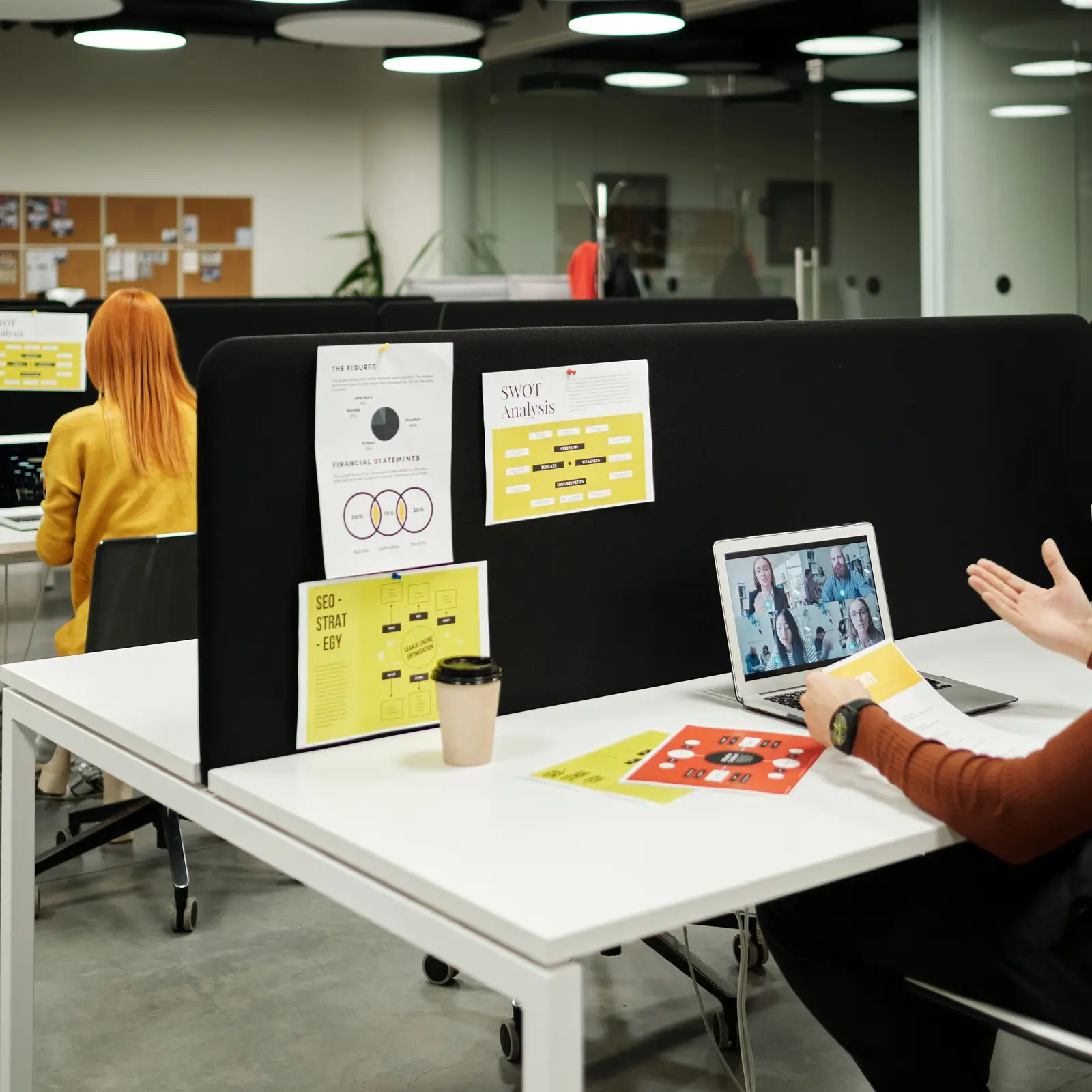 Person on a video call in an open plan office workspace
