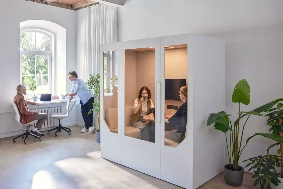 Colleagues using an office pod in an open-plan workspace