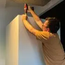 Technician adjusting Persy Booth ceiling panel during installation