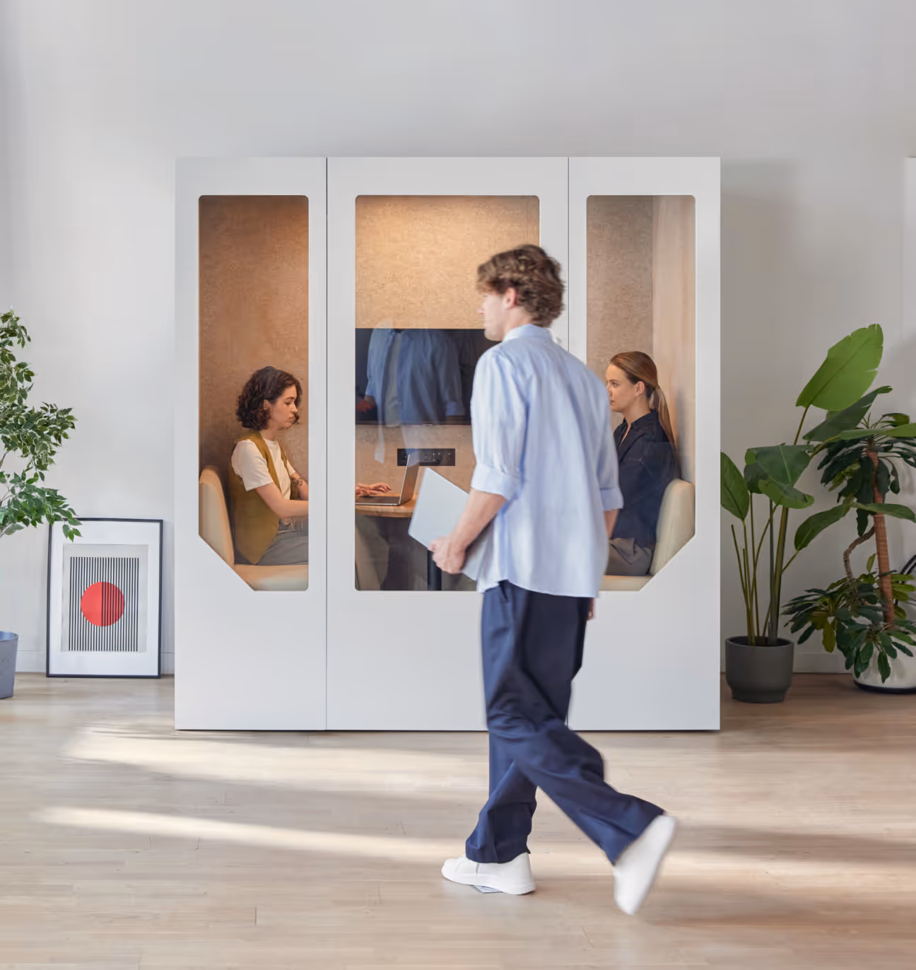 Two people working inside a Persy Booth soundproof pod while another person walks by