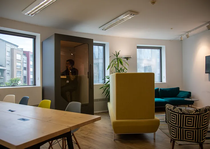 Persy Booths team standing in front of a bright yellow soundproof office pod