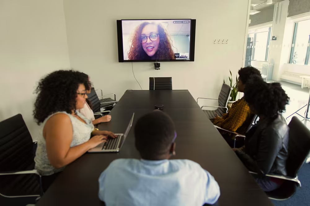 Hybrid team meeting in a huddle room using video conferencing technology