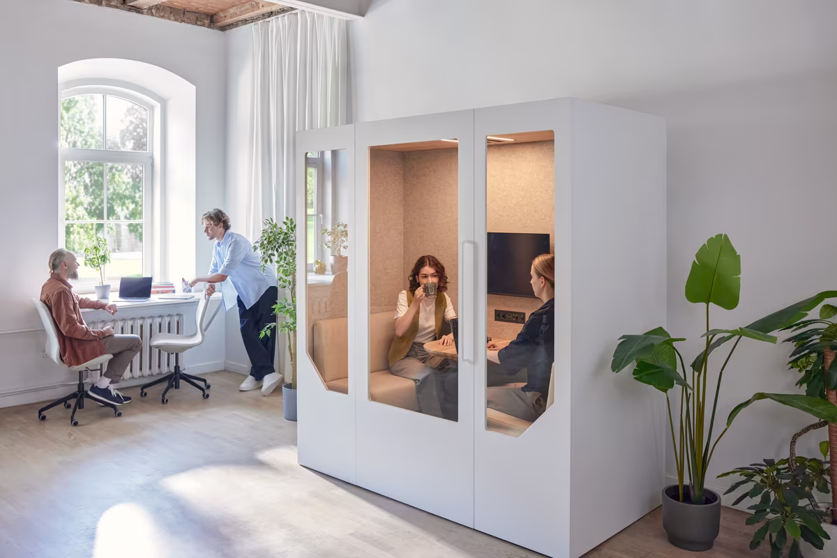 Small team meeting inside a private office meeting pod