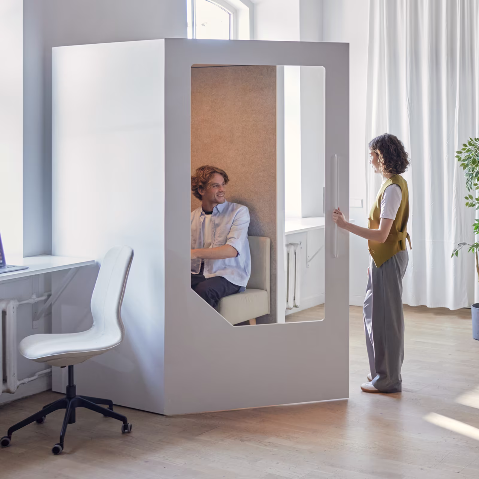 Modern office with Persy soundproof pods in use — one person working in a single booth and another in a meeting pod, showcasing privacy and productivity solutions.