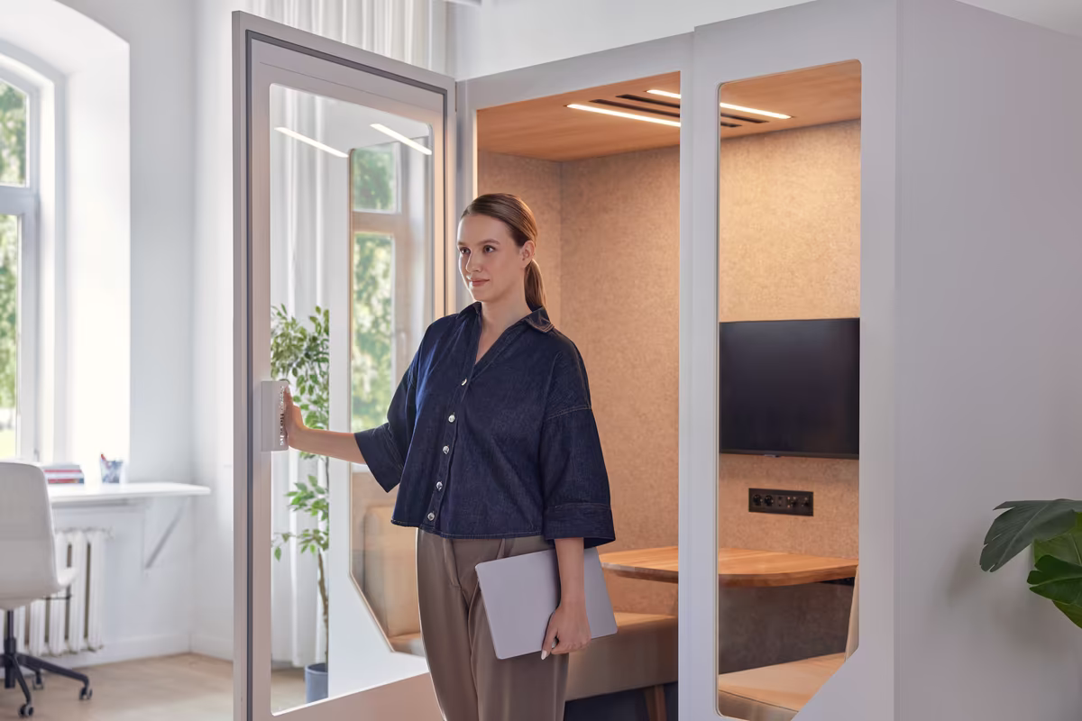 Person working on a laptop inside a soundproof office booth for focused tasks