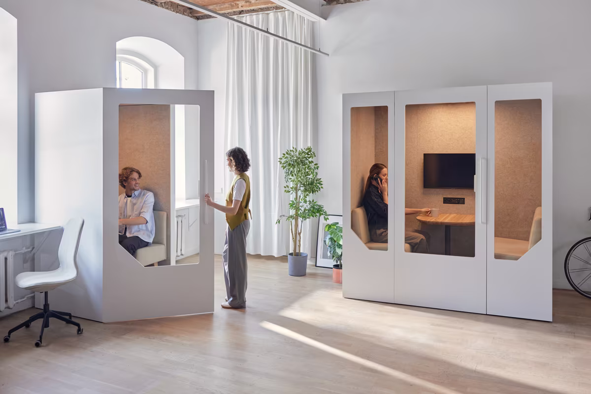 Two people having a focused discussion inside a meeting booth in a modern office