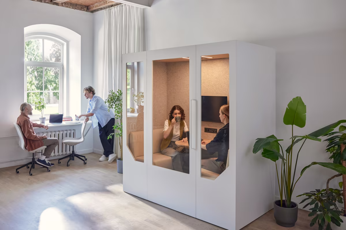Person taking a call inside a soundproof office booth within a shared workspace