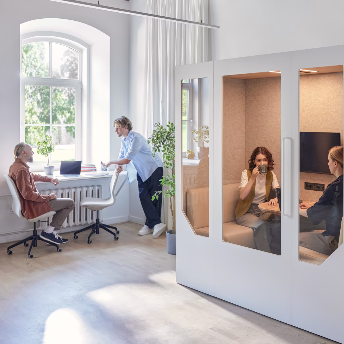 Small team collaborating inside an office meeting pod