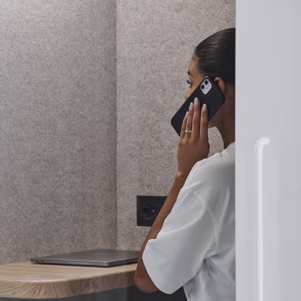 Person taking a phone call inside a soundproof office booth